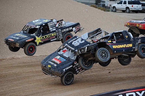 <img src= "racing_pro_lite_trucks.jpg" alt= "pro lite trucks catch air and bump as they race toward the finish line"